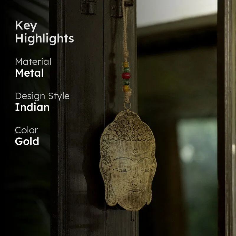 Gold Buddha-face hanging bell displayed by a dark window