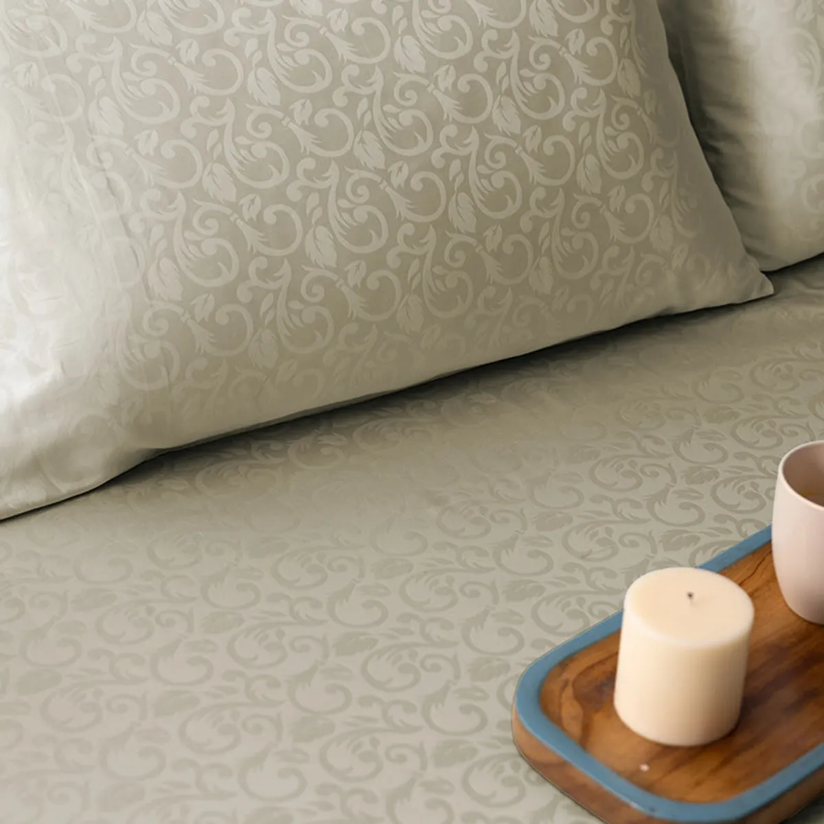 Detailed view of beige patterned bedsheet and pillow beside a bedside tray