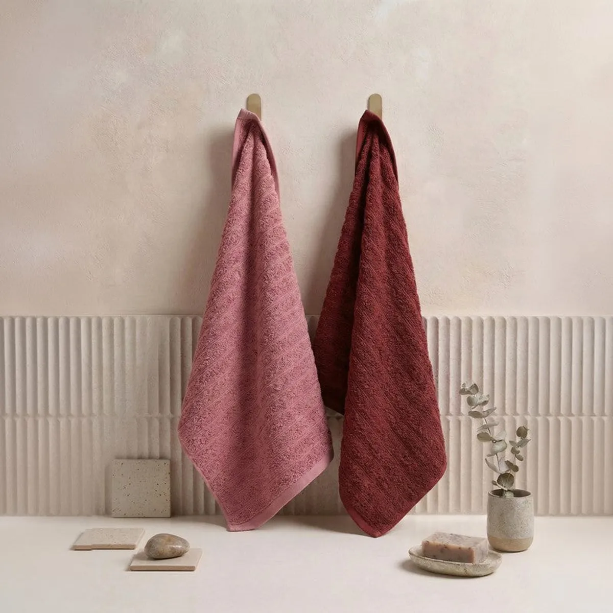 Pink and maroon towels hanging in a bathroom setting