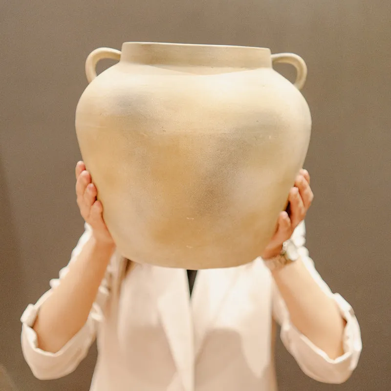 Beige handled ceramic vase held up by a person