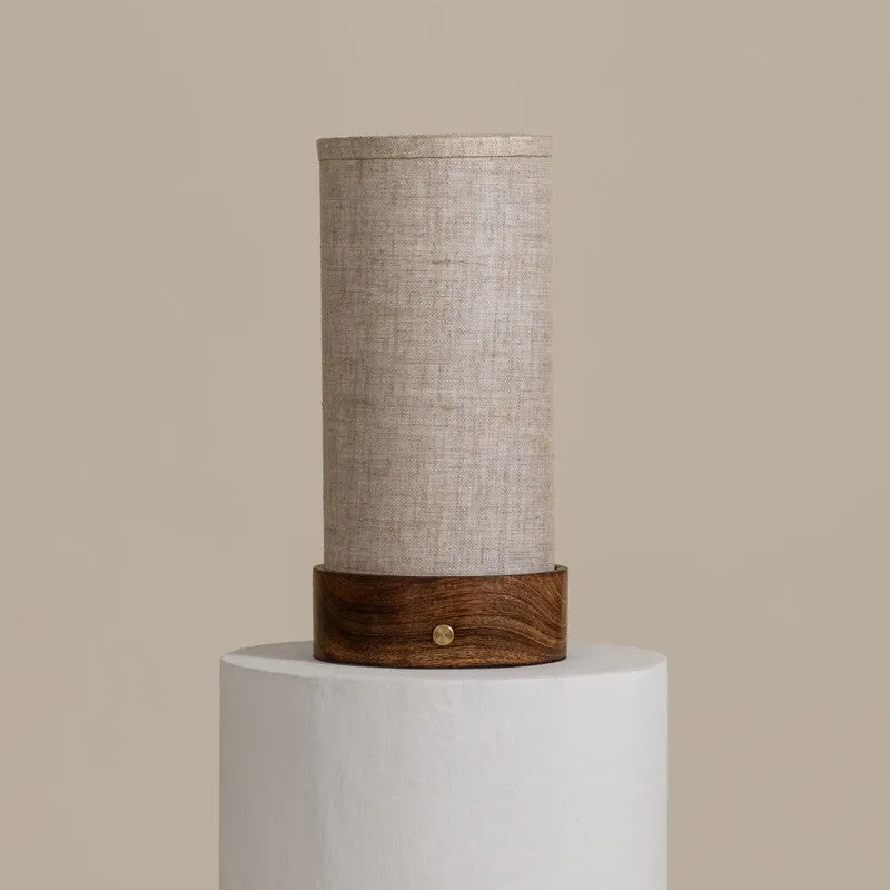 Beige cylindrical touch lamp with wooden base on a white pedestal