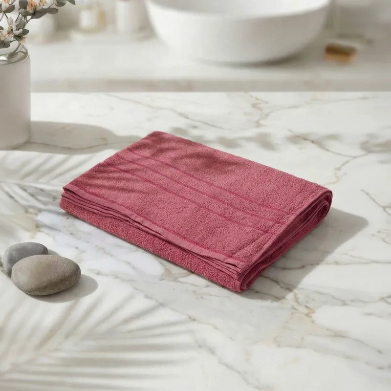 Folded dusty pink bath towel on a marble surface