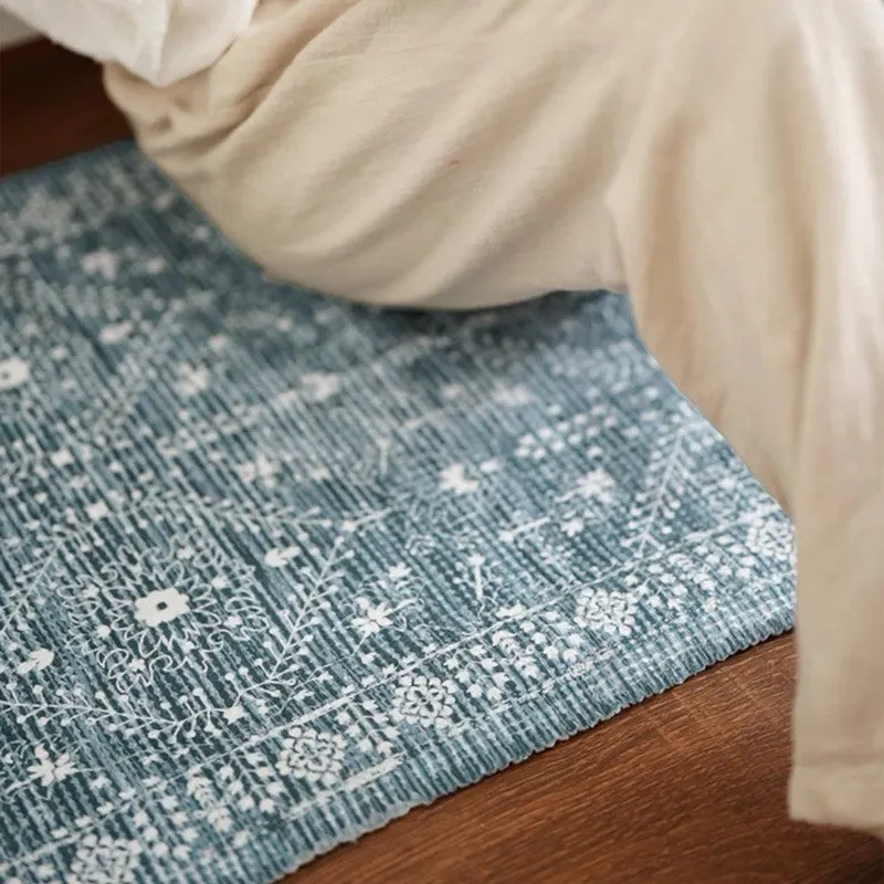Close-up of blue patterned runner rug beside bedding