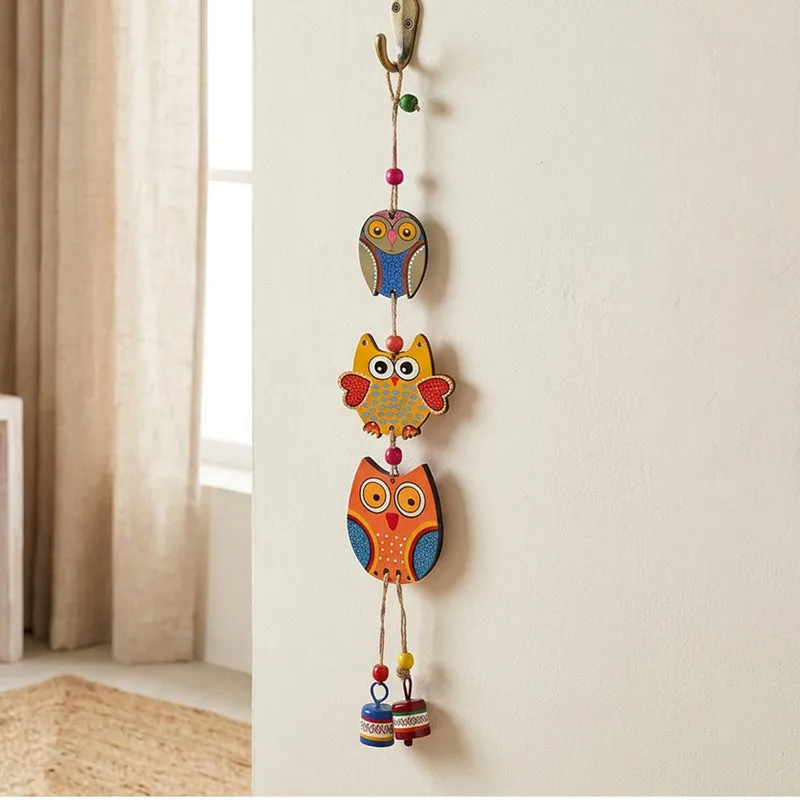 Colourful three-owl windchime hanging from a wall hook
