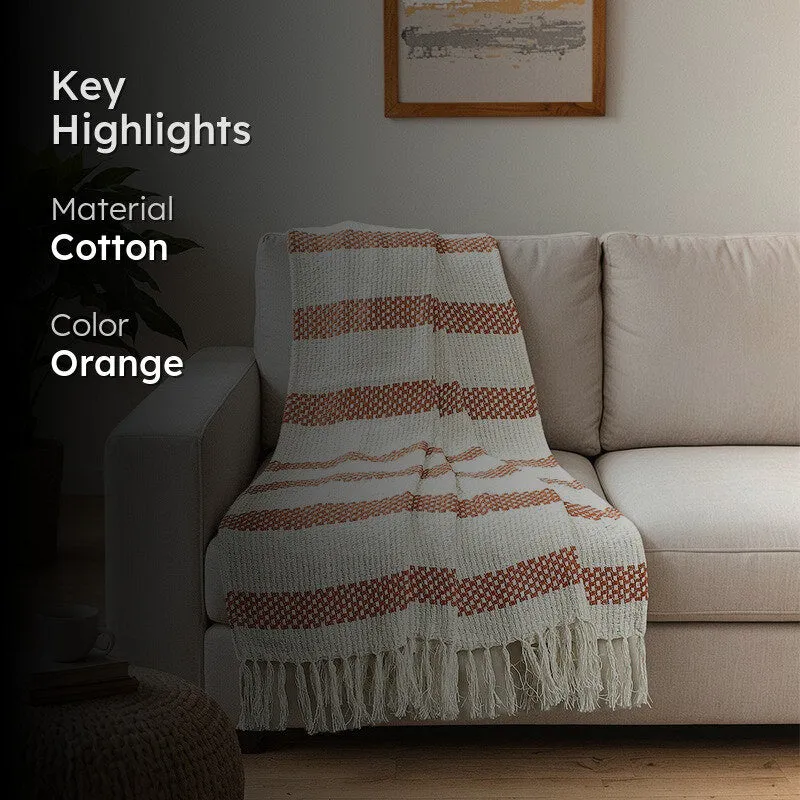 Orange and cream fringed throw styled over a sofa in a living room