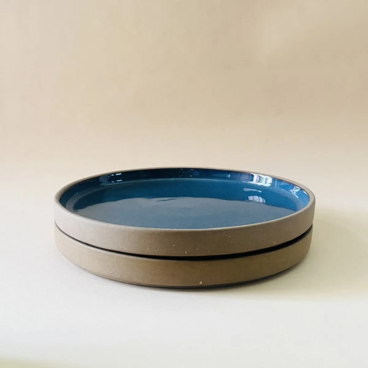 Close-up of stacked blue ceramic quarter plates with raised rims
