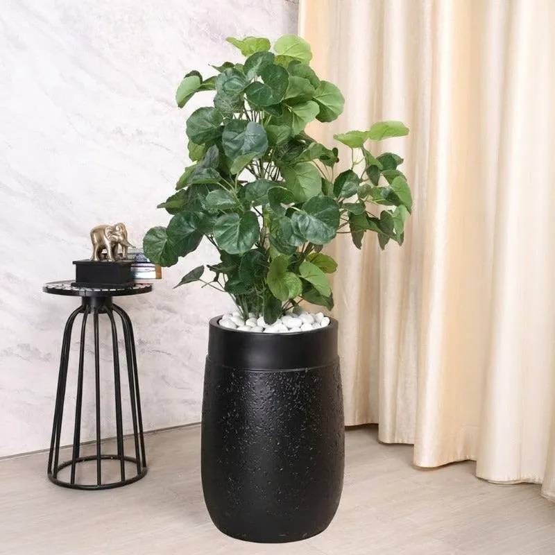 Black floor planter with a leafy plant beside a decorative side table