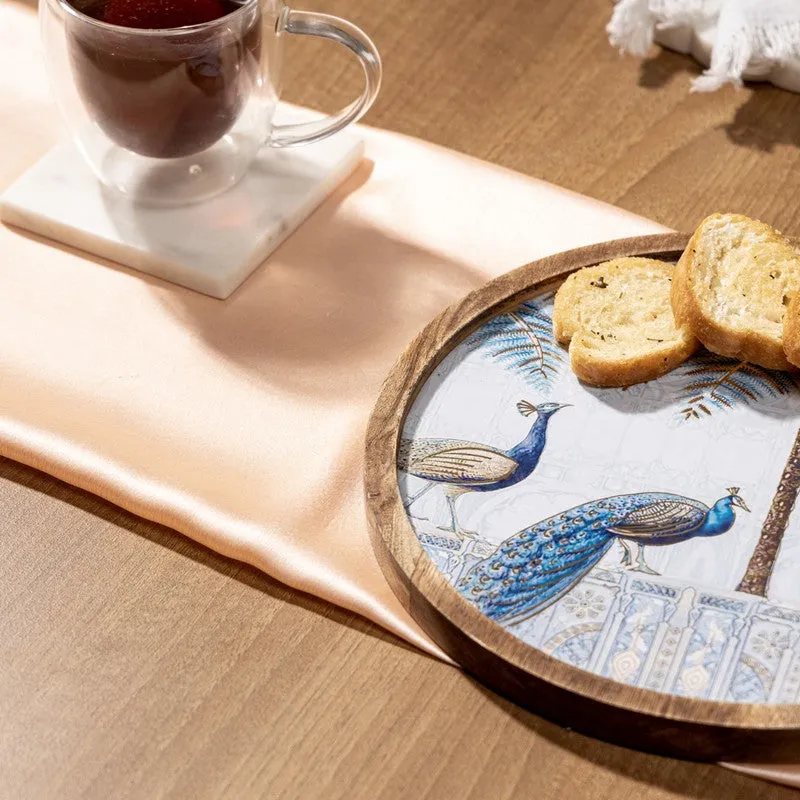 Close-up of blue peacock artwork on the round platter beside a teacup