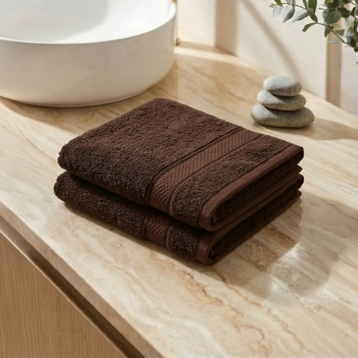Two folded brown hand towels stacked on a bathroom counter