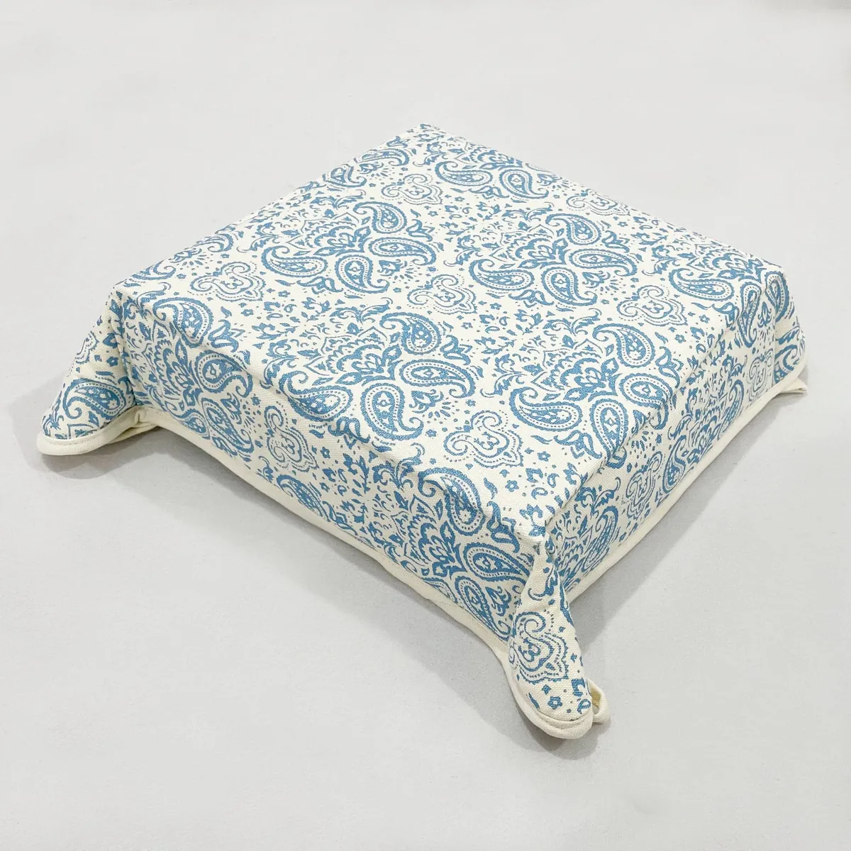 Folded square bread basket in blue paisley print on an off-white base
