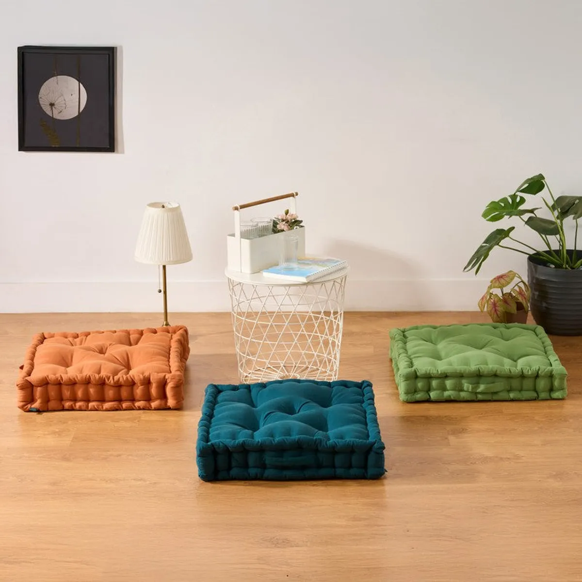 Brown floor cushion arranged on a wooden floor beside colourful cushions