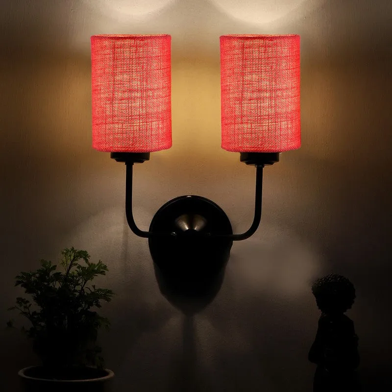 Pink dual-shade wall lamp lit against a dark wall
