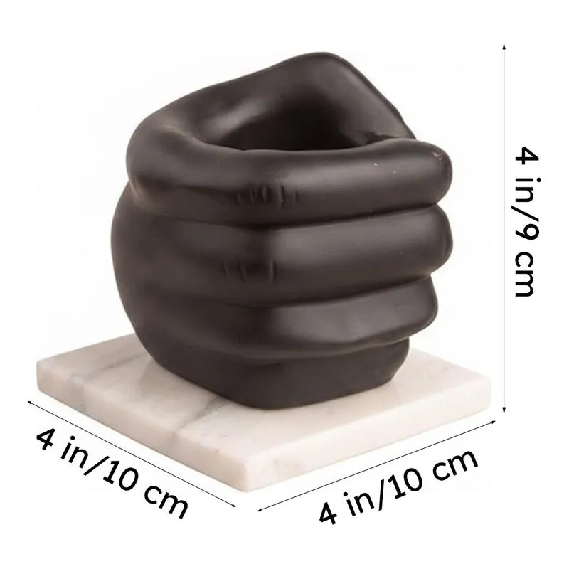 Black fist-shaped pen stand on white marble base