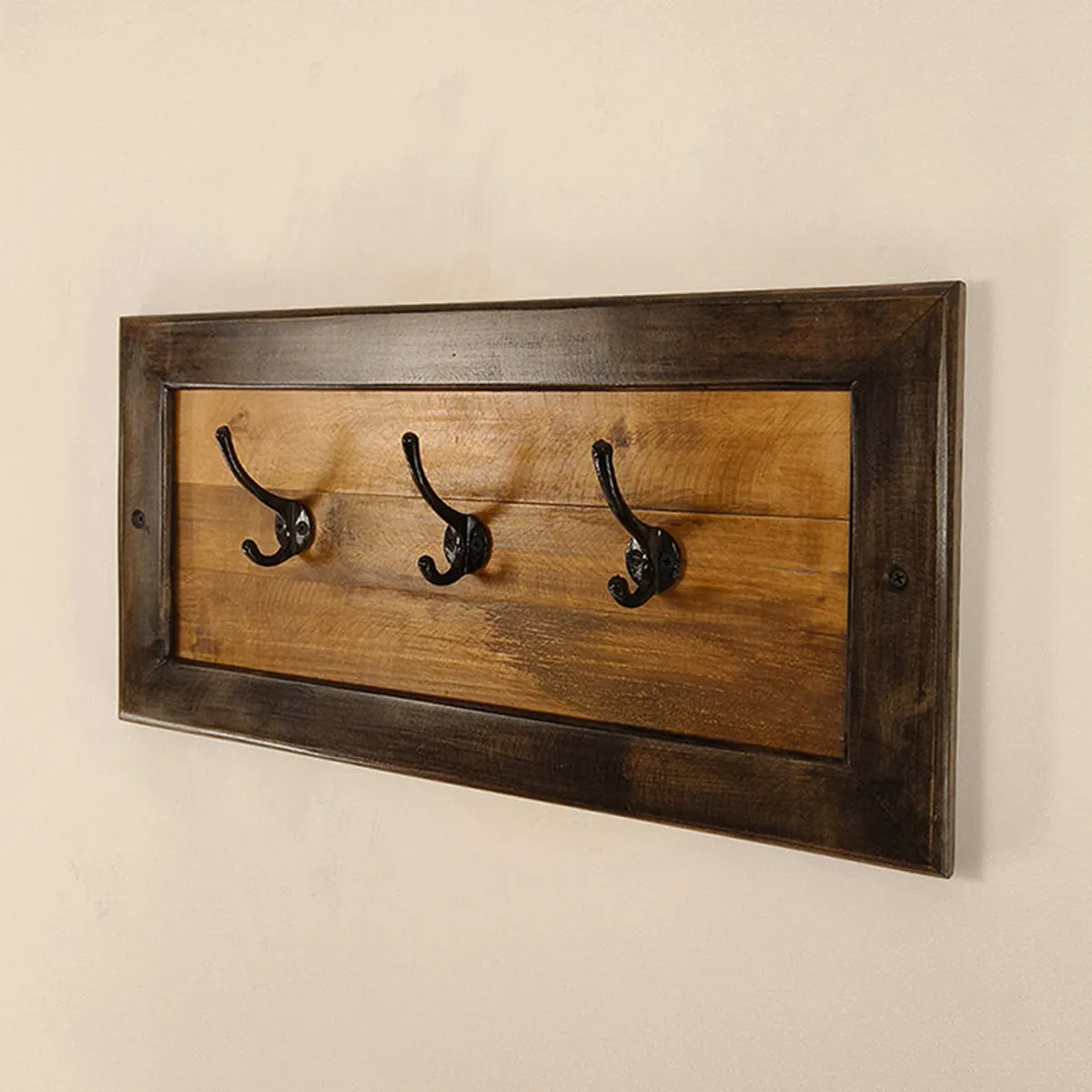 Brown wood wall holder shown empty with black hooks against a light wall.