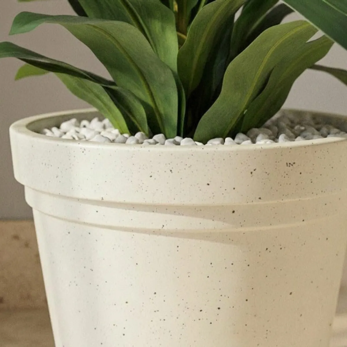 Close-up view of the planter's matte speckled surface and green leaves