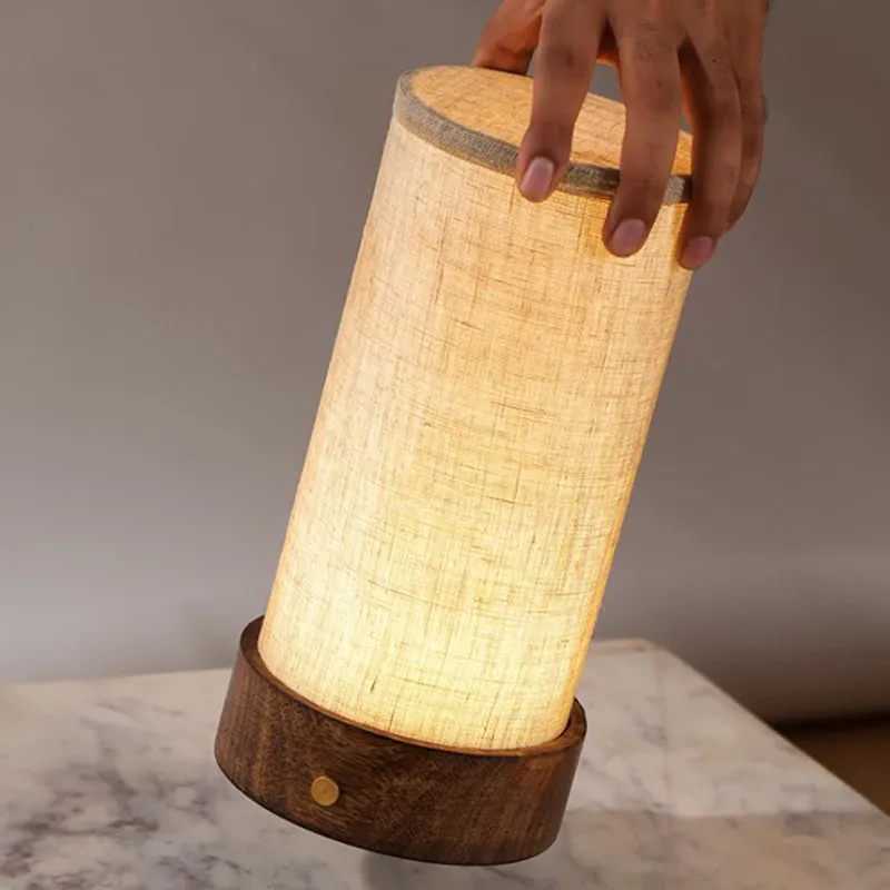 Hand holding the lit cylindrical lamp above a marble surface