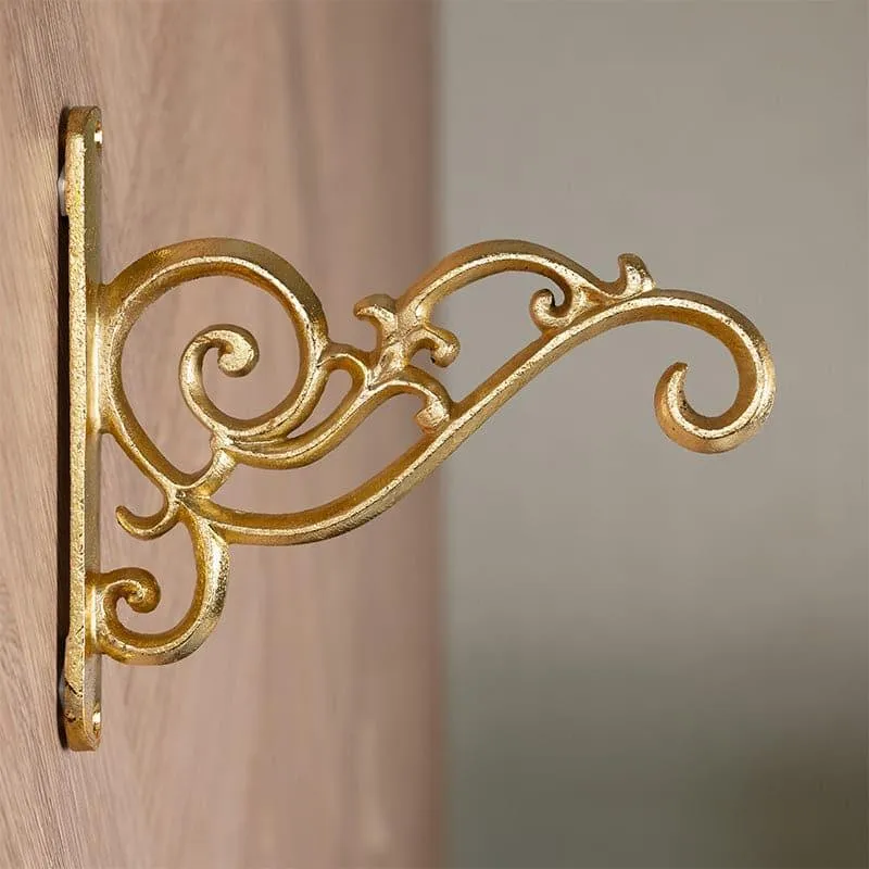 Side view of a gold wall bracket showing its ornate curled design