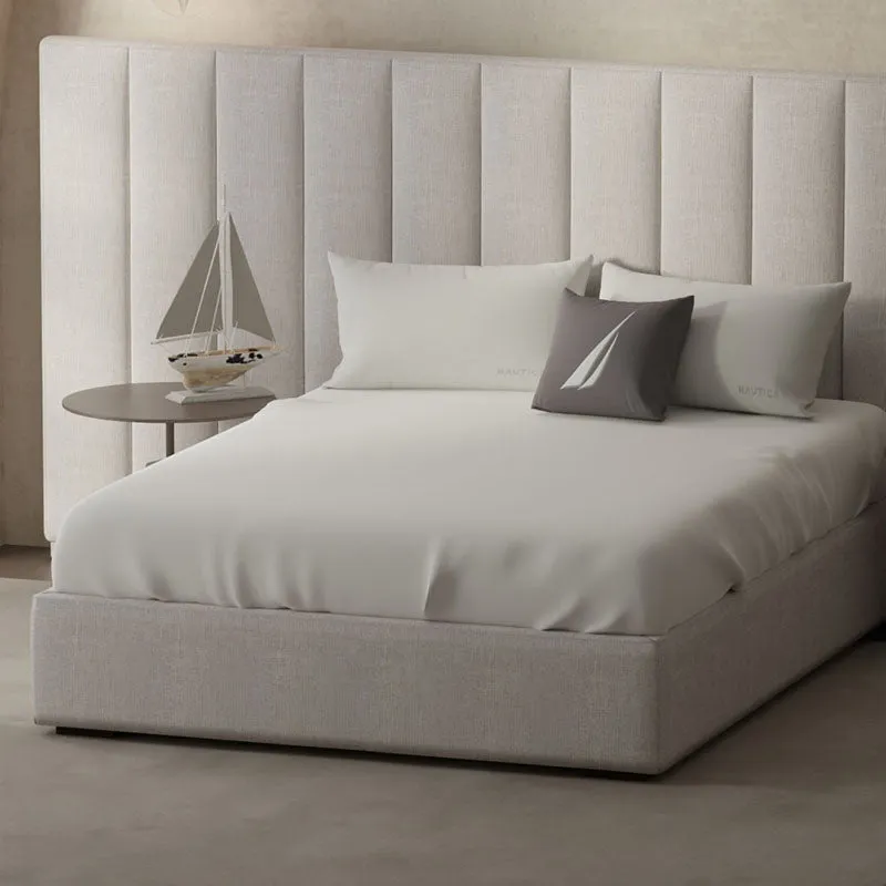 Off white bedsheet styled on a bed with matching pillow covers and a grey accent cushion