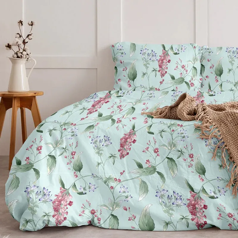 Aqua floral cotton duvet cover styled on a bed with botanical pink, green and purple flowers.