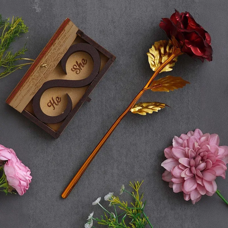 Open wooden gift box and red rose with gold stem on a dark surface
