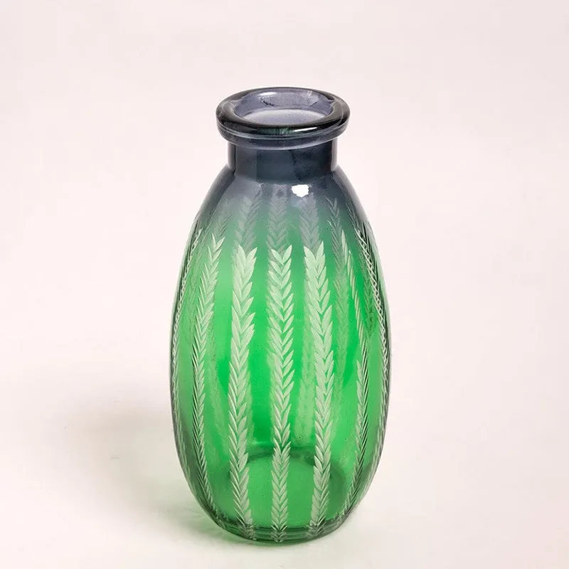 Angled view of a green glass bottle vase with dark top and leaf motif