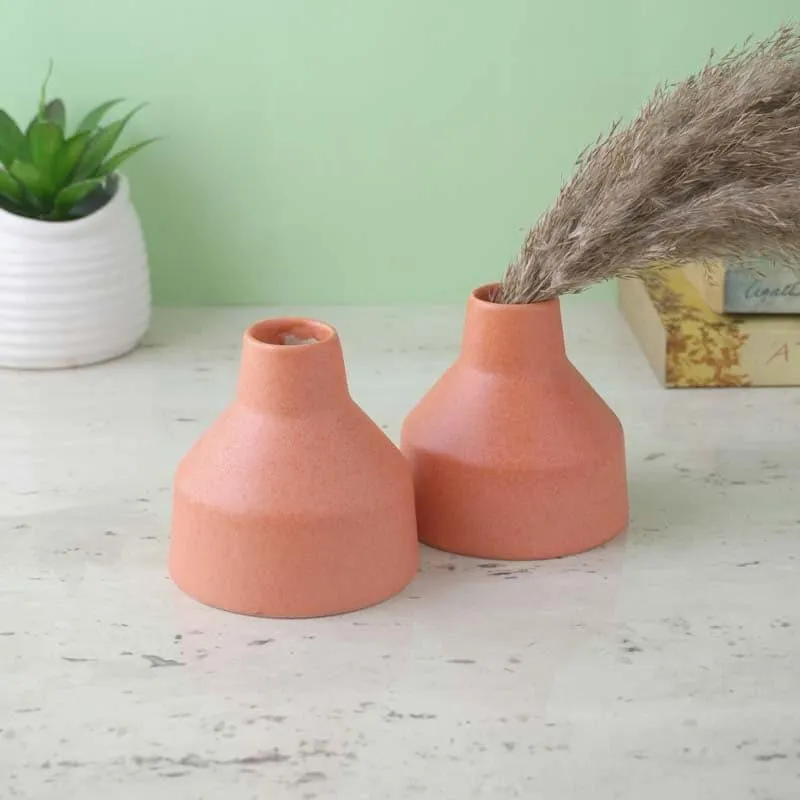 Two blush pink ceramic vases styled on a tabletop, one with dried stems