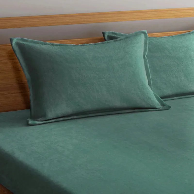 Close-up of matching dark green pillow covers on the bed