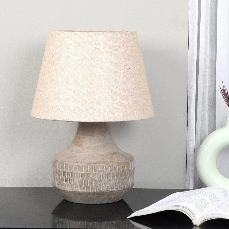 Beige table lamp with textured base and fabric shade styled on a tabletop.