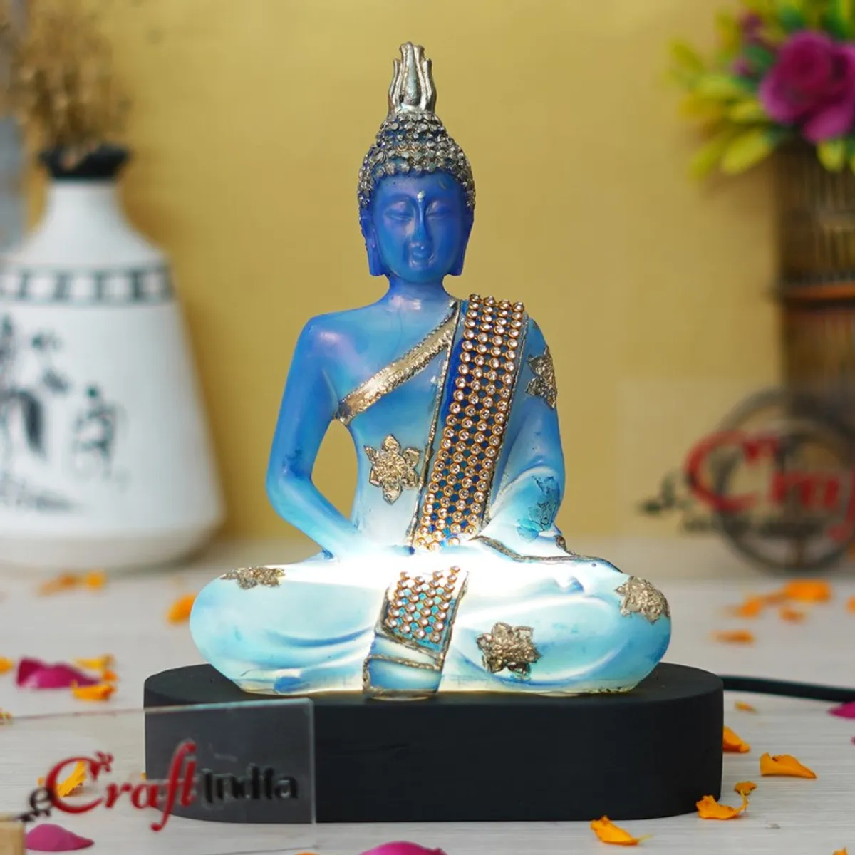 Blue Buddha idol glowing with light on a black base