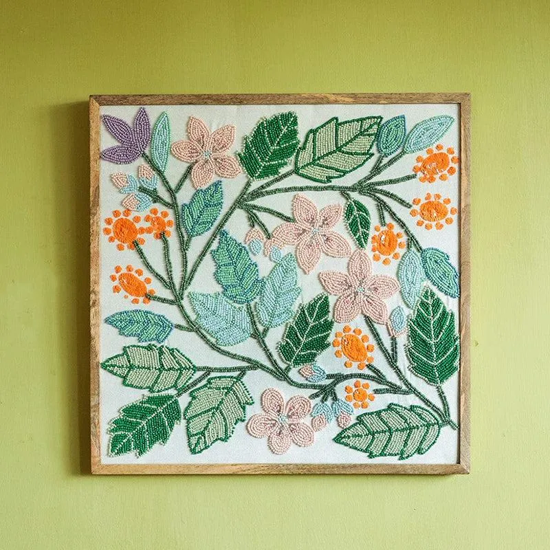 Front view of a square floral wall accent with green leaves, pink flowers and orange blooms