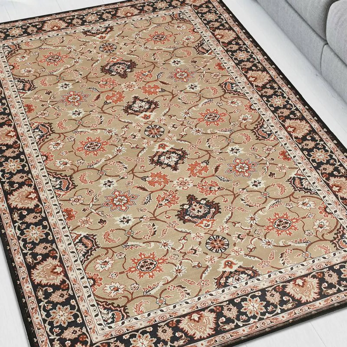 Close view of beige carpet with black border and intricate floral motifs