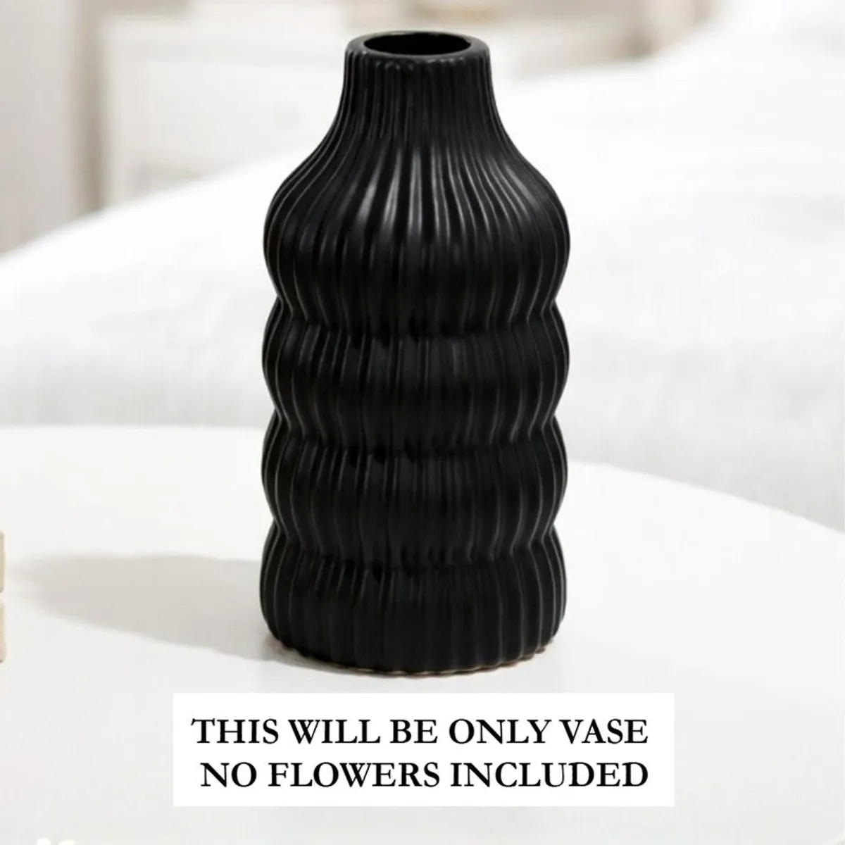 Close-up of a black ribbed vase on a white tabletop