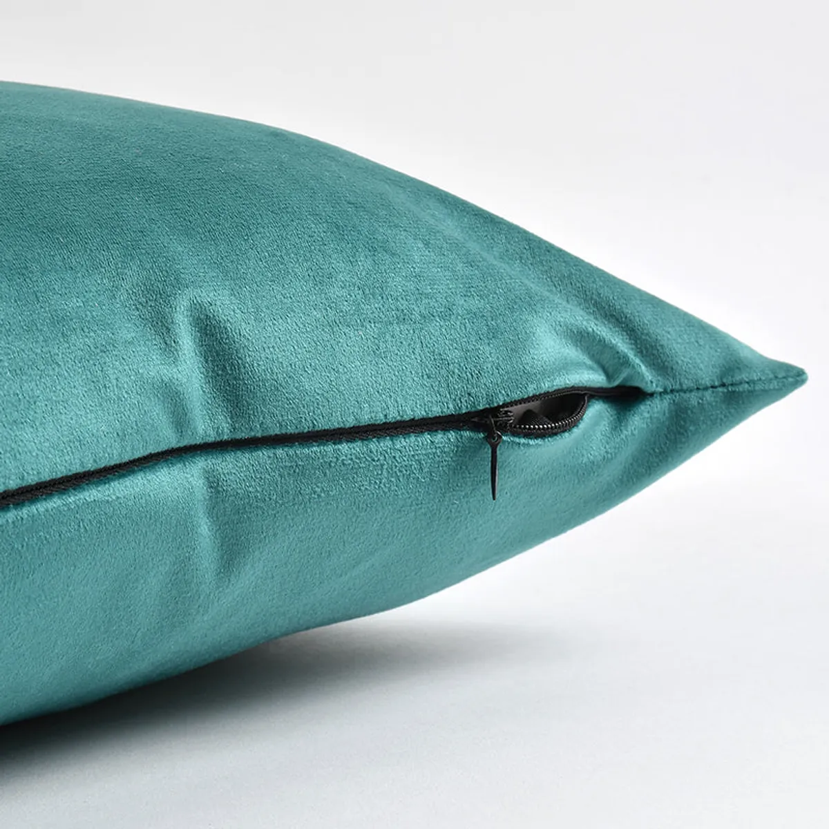 Close-up of the teal velvet cushion cover showing its zip closure.