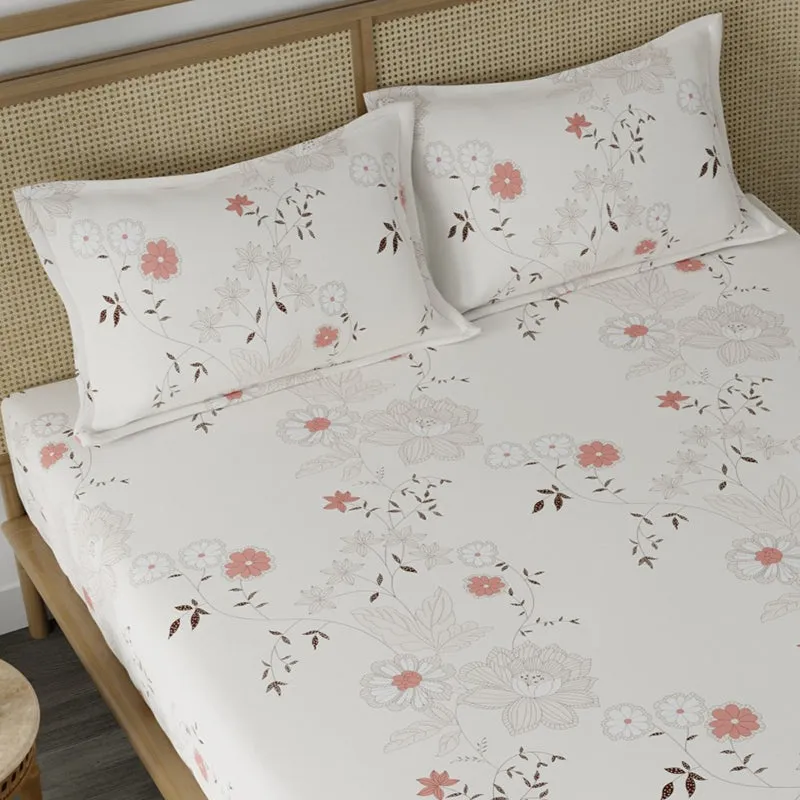 Angled close-up of floral bedsheet and two matching pillow covers on a cane headboard bed