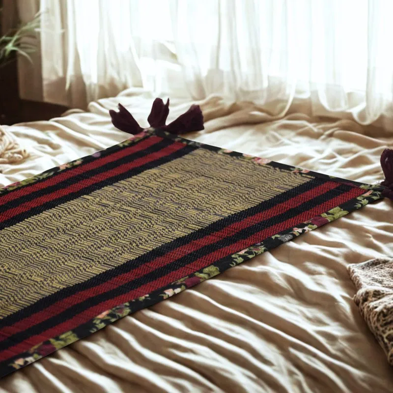 Black, red and beige table runner displayed diagonally on a light bed