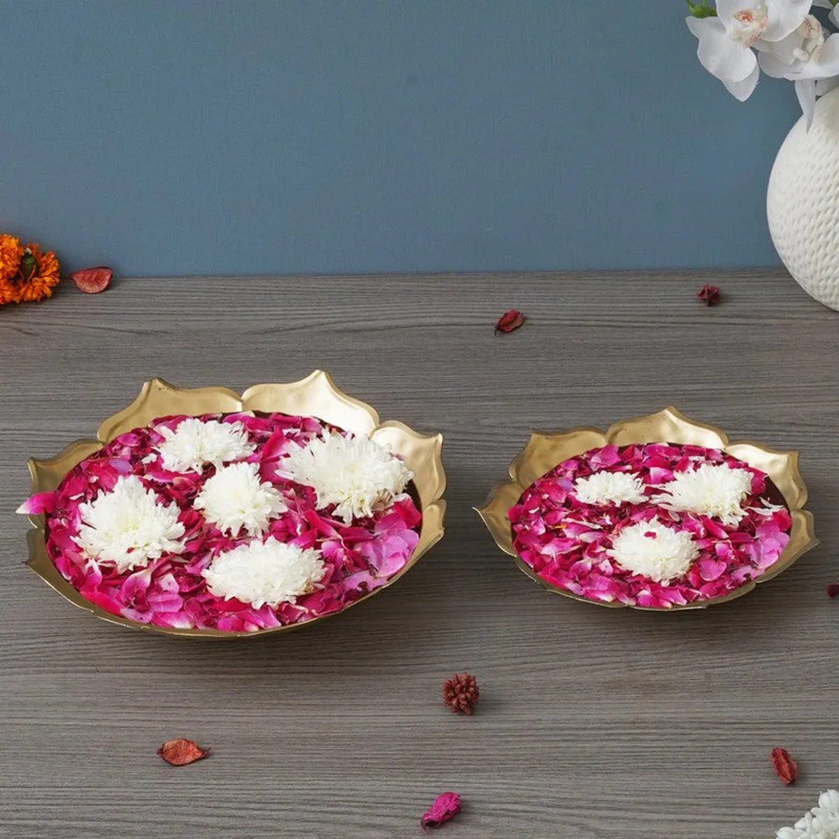 Set of two gold decorative urlis filled with pink petals and white flowers