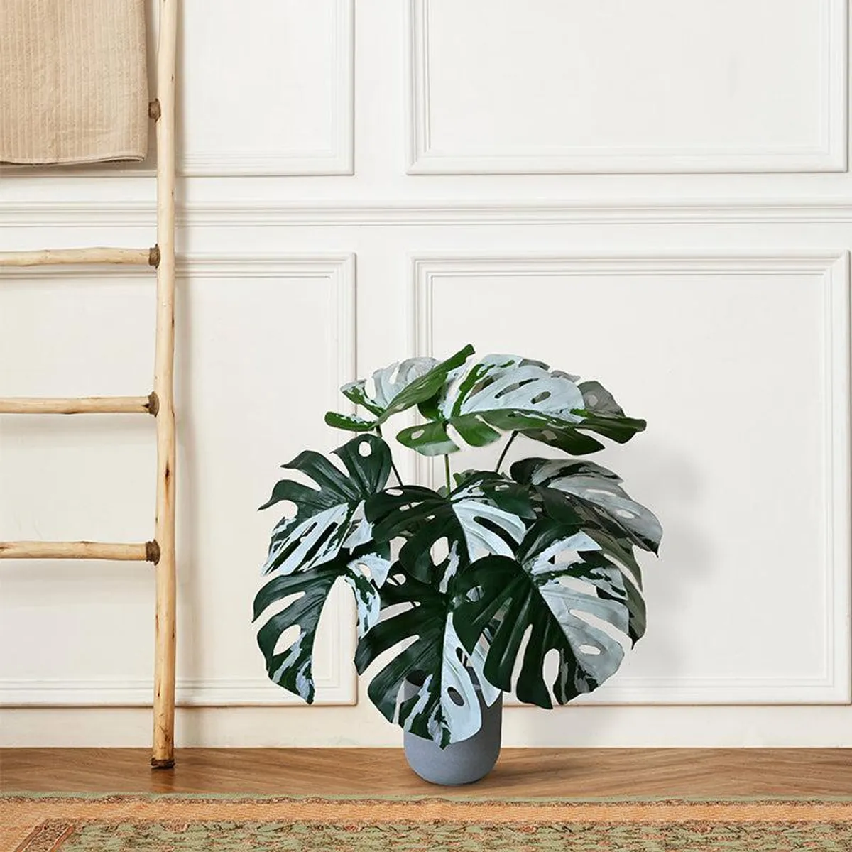 Variegated artificial Monstera plant with green and white leaves in a pot