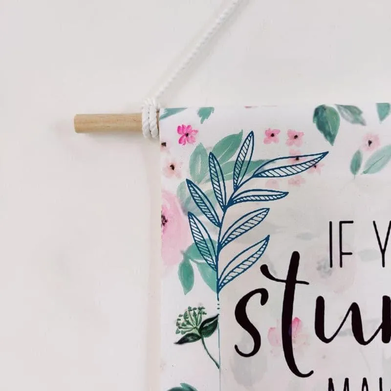Close-up of floral canvas wall hanging with wooden rod and rope