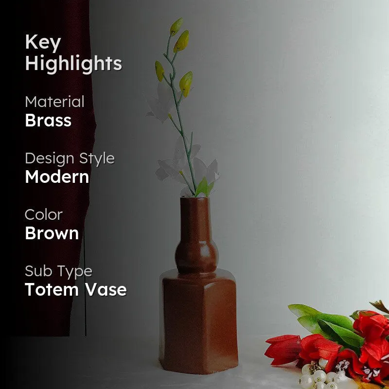 Brown sculptural vase with flowers beside a dark red curtain