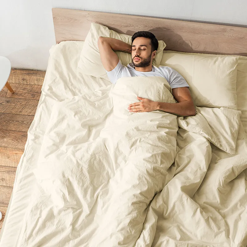 Person resting on a bed dressed in ivory bedding with matching pillow covers