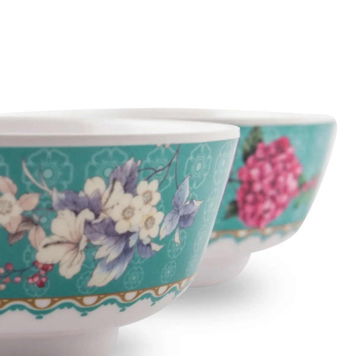 Close-up of two teal bowls showing floral detailing and white interiors.