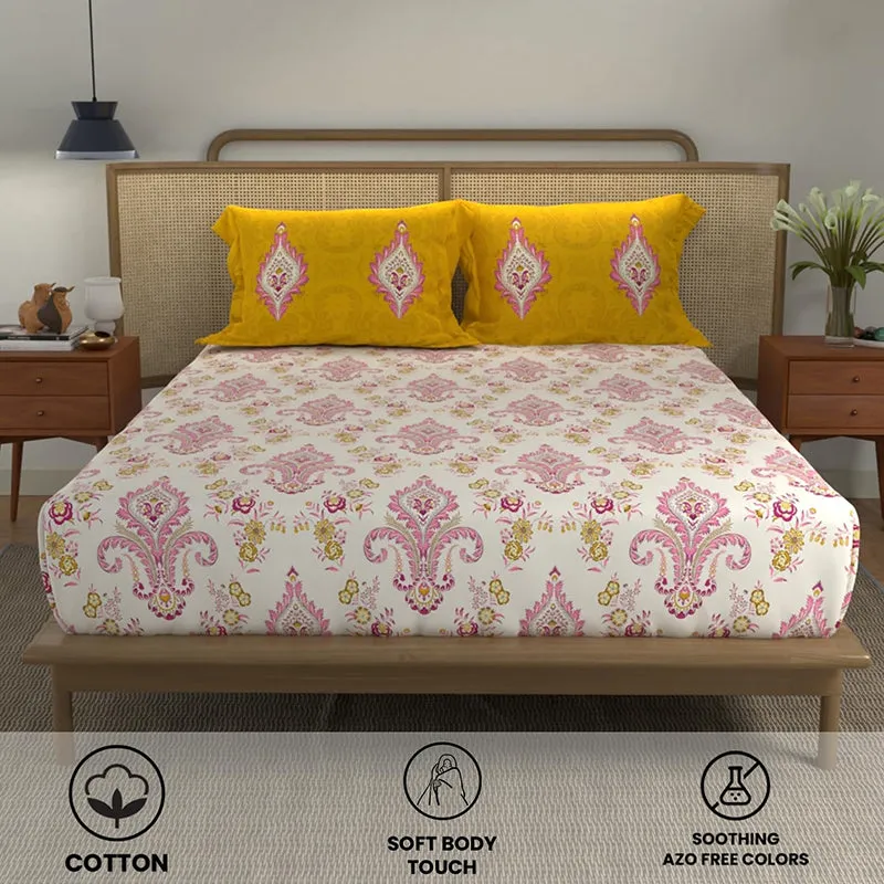 Front view of yellow pillow covers and pink printed bedsheet on a wooden bed