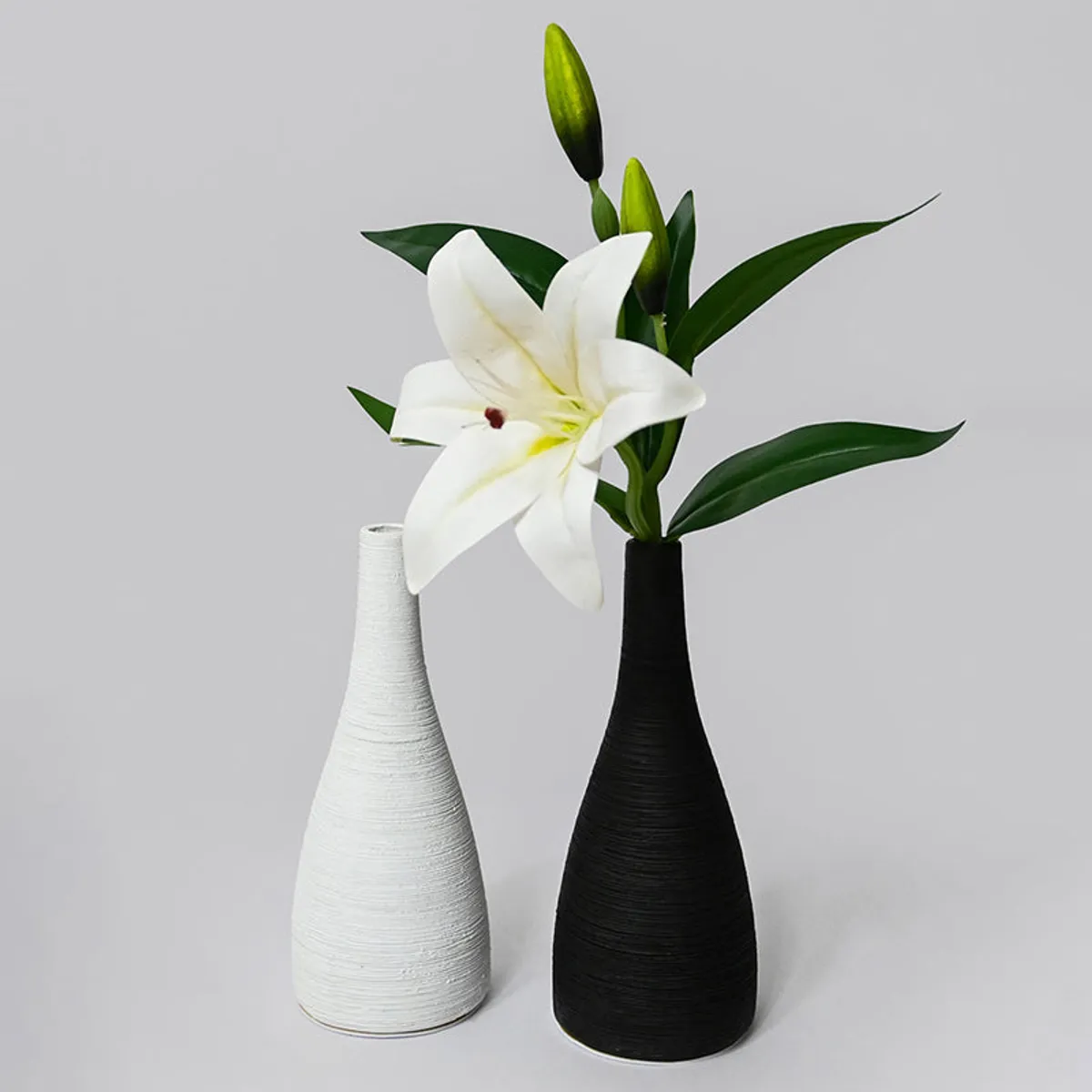 Black and white slender vases, one styled with a white lily