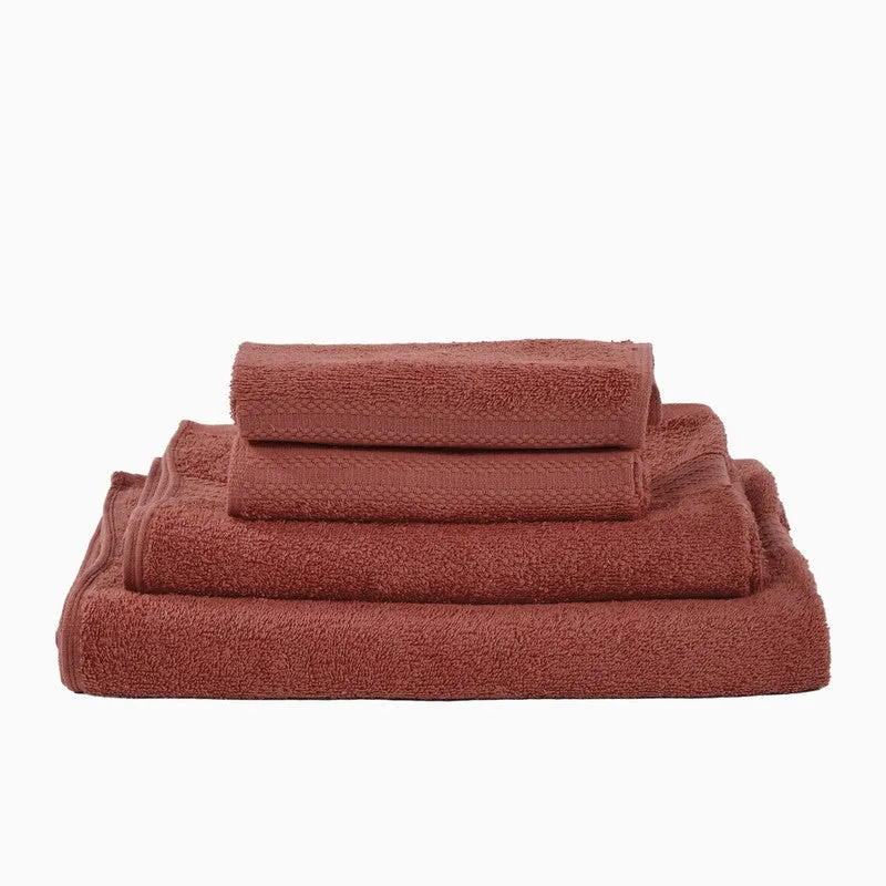 Folded rust towels stacked in a neat pile on a white background