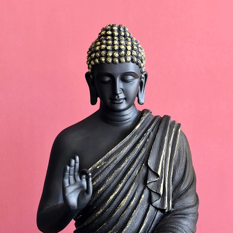 Close-up of black Buddha idol with gold detailing on the head and robe