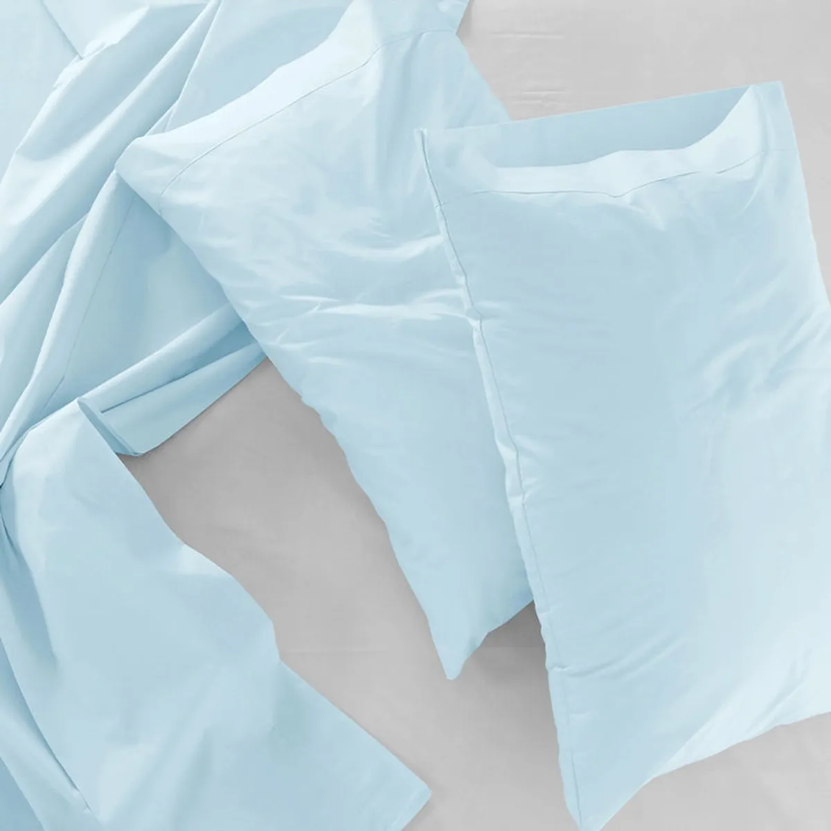 Pale blue pillow covers arranged flat with matching bedding.
