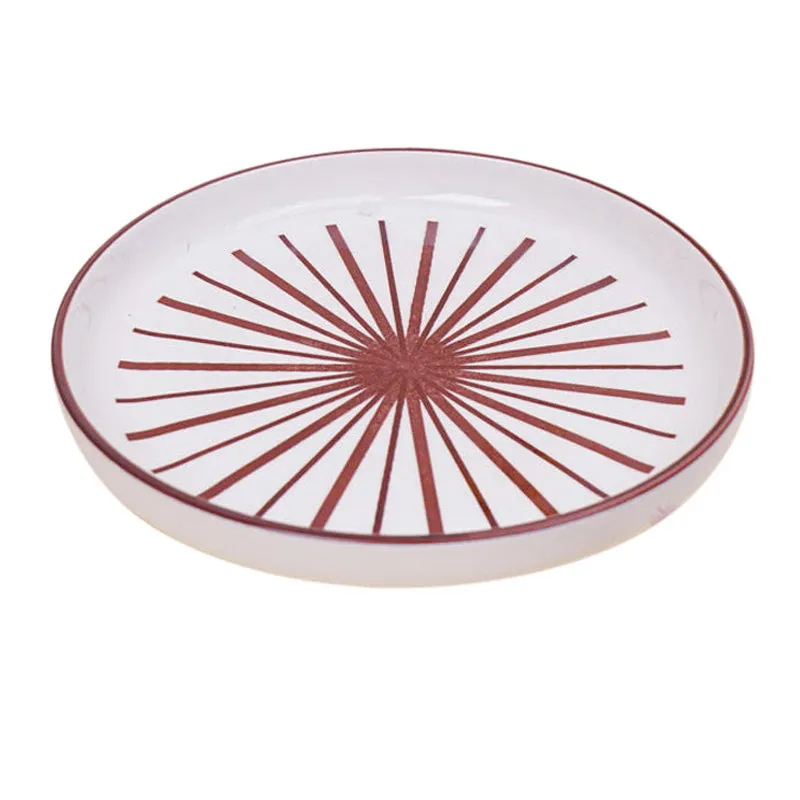 Single white porcelain plate with maroon starburst pattern on white background