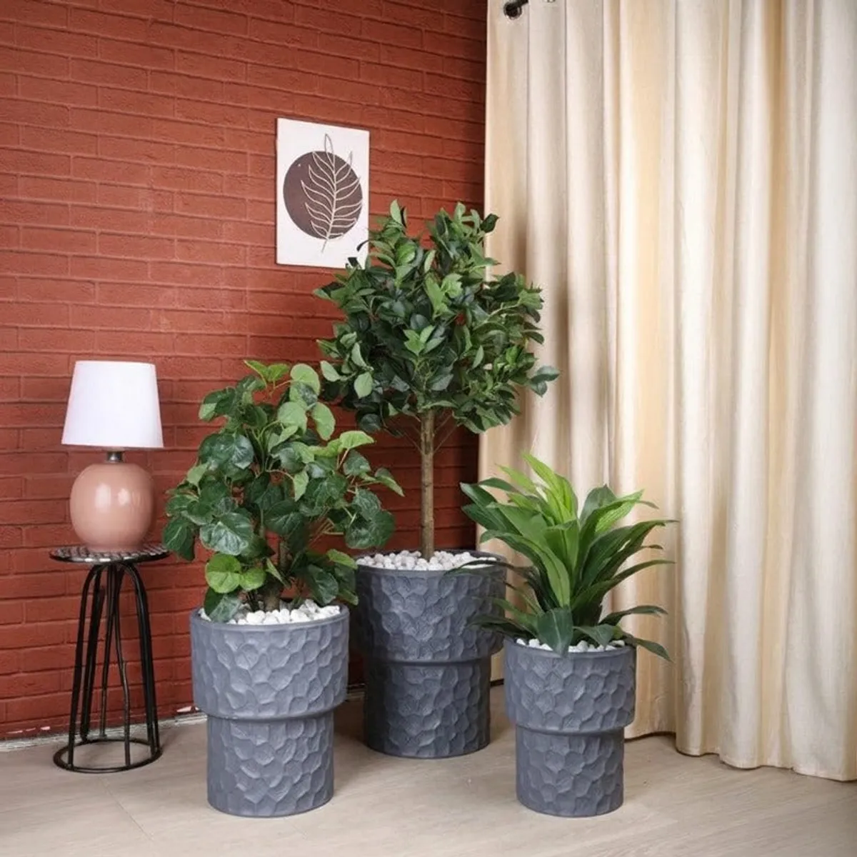 Three grey textured planters displayed together with indoor plants