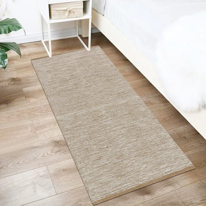 Beige runner rug placed beside a bed on a wooden floor