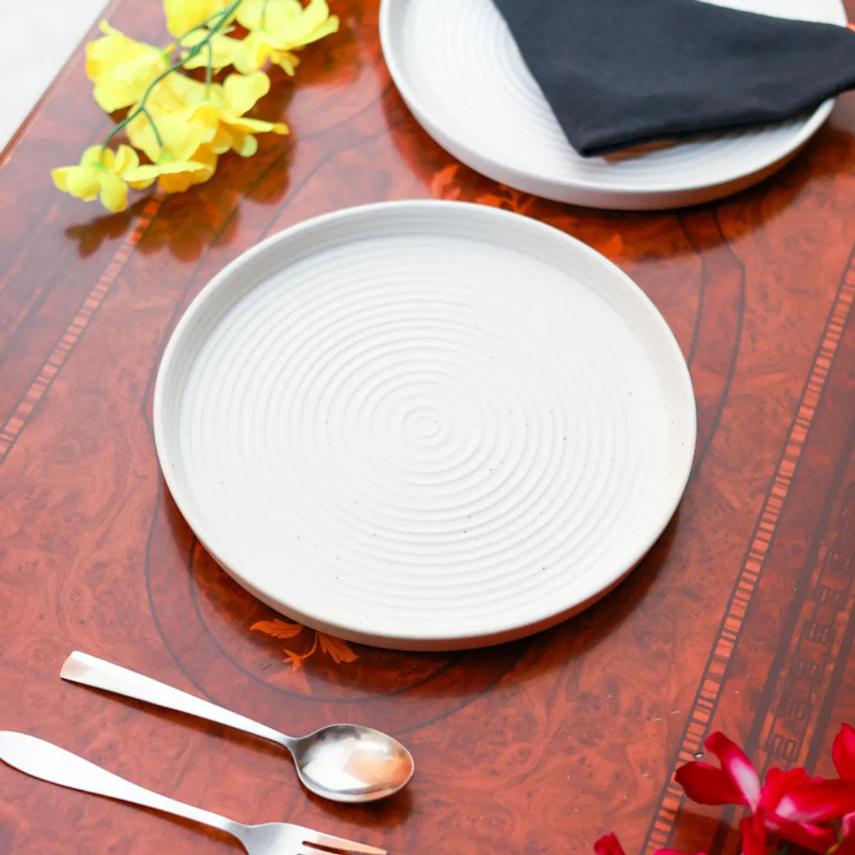White concentric-circle ceramic plate arranged on a dining table